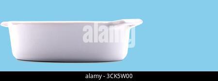 A white ceramic baking dish with handles, suitable for cooking and serving various dishes. Stock Photo