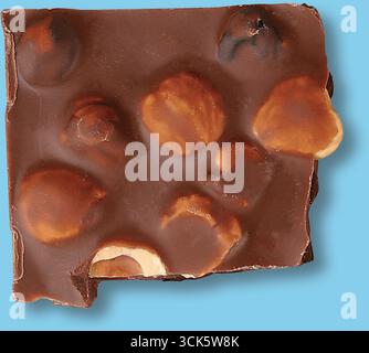 A square piece of chocolate with visible hazelnuts embedded in it. Stock Photo