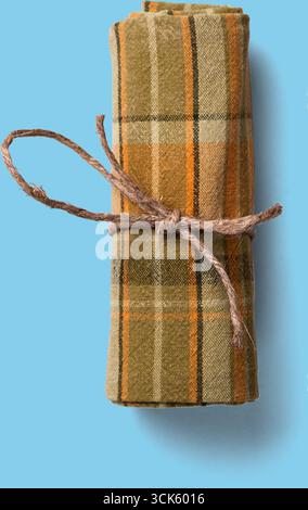 A rolled-up plaid fabric tied with twine, suggesting a cozy and rustic aesthetic. Stock Photo