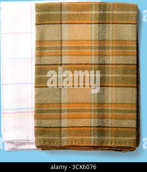 Two folded towels, one with a plaid pattern in green and orange, the other white with colorful stripes. Stock Photo