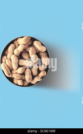 A bowl filled with unpeeled peanuts, showcasing their natural texture and color. Stock Photo