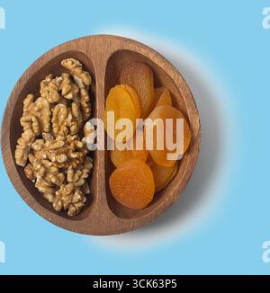 A wooden bowl containing walnuts and dried apricots, perfect for snacking or healthy eating. Stock Photo