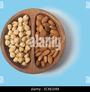 A wooden bowl divided into two sections, one containing hazelnuts and the other containing almonds, showcasing healthy snacks. Stock Photo