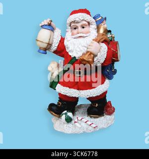 A festive Santa Claus figurine holding a lantern, surrounded by gifts and toys, embodying the spirit of Christmas. Stock Photo