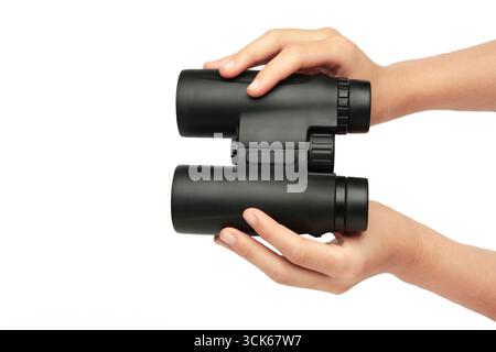 Female hand holds black binoculars isolated on white background. Looking through binoculars, journey, find and search concept. Top view Stock Photo