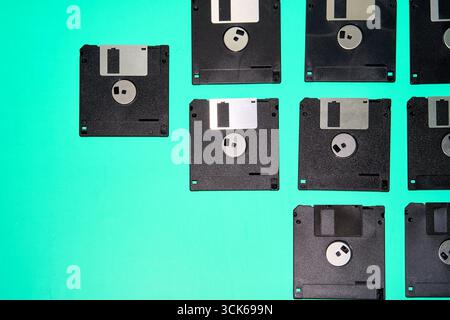 A collection of old floppy disks, relics of 90s computing, arranged in a grid on a turquoise background Stock Photo