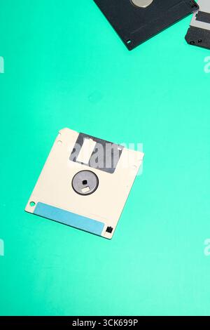 An isolated 3.5 inch floppy disk, featuring a blue label, is placed on a smooth turquoise surface Stock Photo