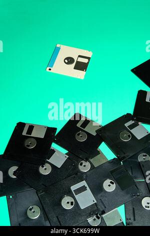 A collection of obsolete floppy disks, artifacts from the digital age of the 90s, arranged haphazardly on a turquoise background Stock Photo