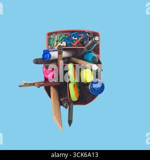 A collection of stationery items including pens, markers, and paper clips organized in a container. Stock Photo