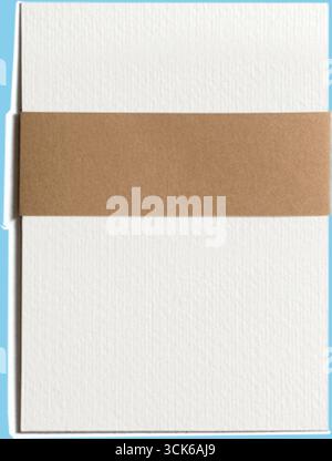 A simple, textured white card wrapped with a brown band, suggesting a minimalist design for invitations or stationery. Stock Photo