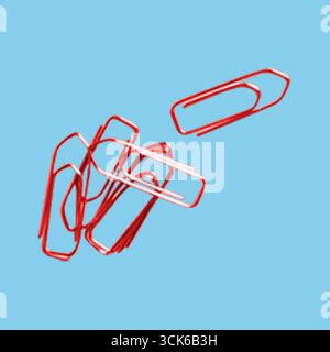 A collection of red paper clips scattered on a surface, commonly used for organizing papers. Stock Photo