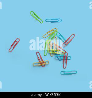 A colorful assortment of paper clips scattered on a surface, showcasing various vibrant hues for organizational use. Stock Photo