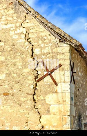 Large structural crack with retaining metal X-braces on old stone barn end wall - central France. Stock Photo