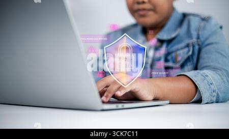 Business hand typing on laptop with digital shield icon and lock symbol representing cyber security, data protection, privacy, and online safety for m Stock Photo