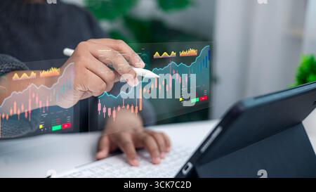 Businessman hand using digital pen analyzing stock market data and financial graph on futuristic screen with tablet computer for investment and tradin Stock Photo