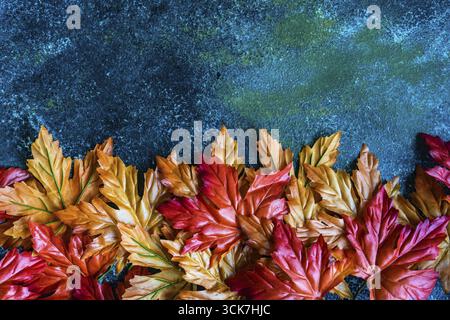 Bright red and yellow fake maple leaves on the concrete background Stock Photo