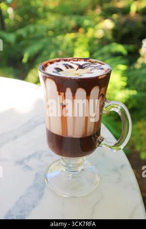 Cup of mouthwatering rich hot cocoa latte served on round garden table Stock Photo