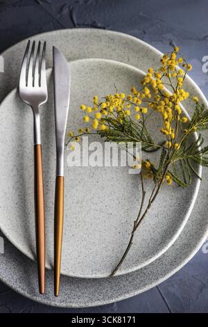Festive table setting with mimosa flowers for easter holiday dinner Stock Photo