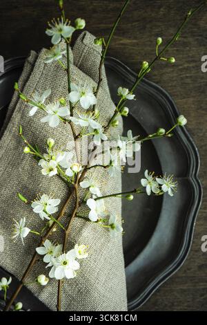 Feastive table setting for holiday Easter dinner decorated with blooming cherry flowers on rustic table with copy space Stock Photo