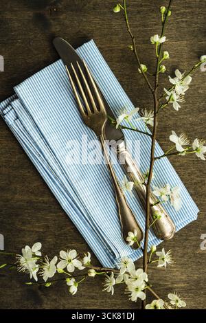 Feastive table setting for holiday Easter dinner decorated with blooming cherry flowers on rustic table with copy space Stock Photo