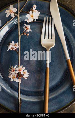 Spring table setting with peach blooming tree branch on wooden background with copy space Stock Photo