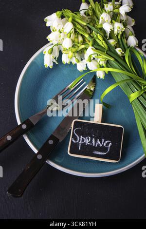 Feastive table setting for holiday Easter dinner decorated with spring snowdrop flowers on rustic table with copy space Stock Photo