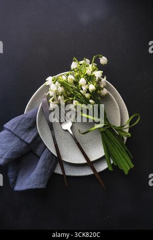 Feastive table setting for holiday Easter dinner decorated with spring snowdrop flowers on rustic table with copy space Stock Photo