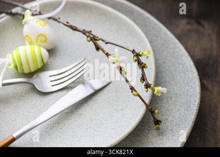 Feastive table setting for holiday Easter dinner decorated with blooming cherry flowers on rustic table with copy space Stock Photo
