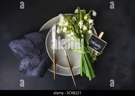 Feastive table setting for holiday Easter dinner decorated with spring snowdrop flowers on rustic table with copy space Stock Photo