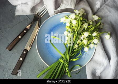 Feastive table setting for holiday Easter dinner decorated with spring snowdrop flowers on rustic table with copy space Stock Photo