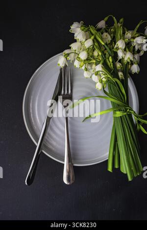 Feastive table setting for holiday Easter dinner decorated with spring snowdrop flowers on rustic table with copy space Stock Photo