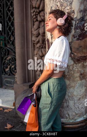 Young woman listening music with headphones and shopping bags Stock Photo