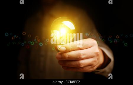Hand holding illuminated light bulb representing inspiration, smart thinking, creativity, and future technology innovation for business success and pr Stock Photo