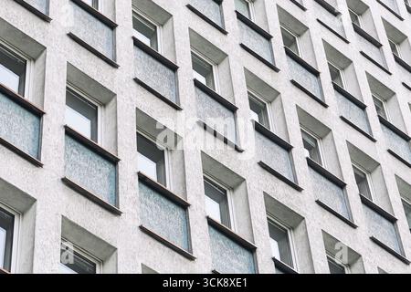 Facade of apartment building with repetitive windows. Urban residential block exterior. Modern architecture with geometric pattern design. Stock Photo