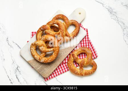 Cutting board with tasty pretzels on marble background, closeup Stock Photo
