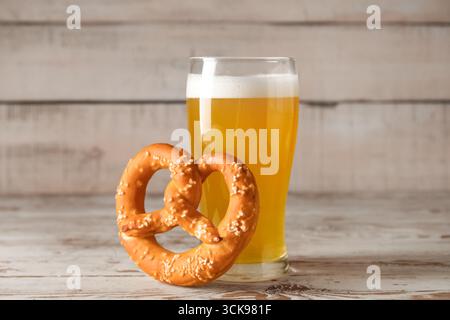 Glass of cold beer and tasty pretzel on wooden background, closeup Stock Photo