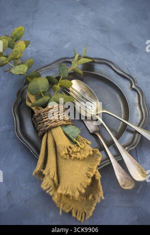 Rustic table setting with vintage silverware and plates on concrete table Stock Photo