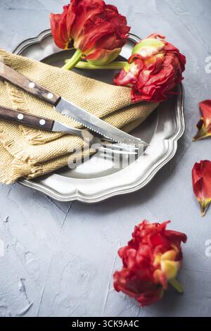 Summer table setting decorated with Red Princess tulips on rustic background Stock Photo