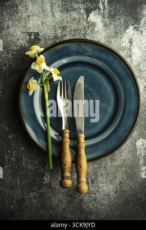Minimalistic spring table setting decorated with fresh daffodil flowers on concrete background Stock Photo