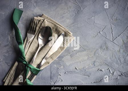 Cutlery set with green ribbon and silverware on linen napkin Stock Photo