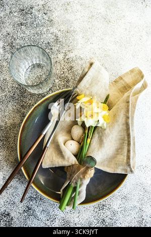 Minimalistic table setting for easter festive dinner decorated with daffodil flowers Stock Photo
