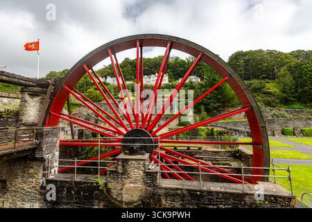 Laxey, Isle of Man 08,05,2023 Large red wheel with a flag on top of it. The flag is orange and white. The wheel is surrounded by a fence Isle of Man - Stock Photo