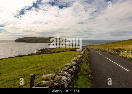 Port Erin, Isle of Man 08,05,2023 Road with a stone wall on the side and a body of water in the background. The road is empty and the sky is cloudy Is Stock Photo