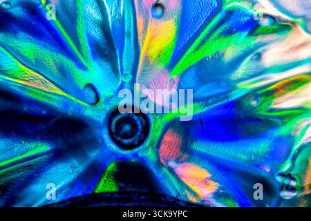 A vibrant close-up of crystal glass under direct light, showing radiant refractions and abstract patterns in red, blue, green, yellow, and orange hues Stock Photo