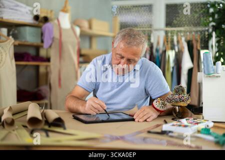 Man tailor makes pattern using tablet Stock Photo