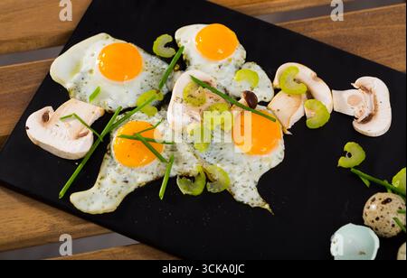 Broken fried quail eggs with mushrooms Stock Photo