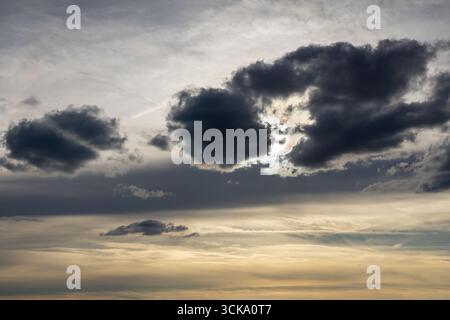 Dramatic sky with sun rays breaking through dark storm clouds and moody atmosphere. Stock Photo