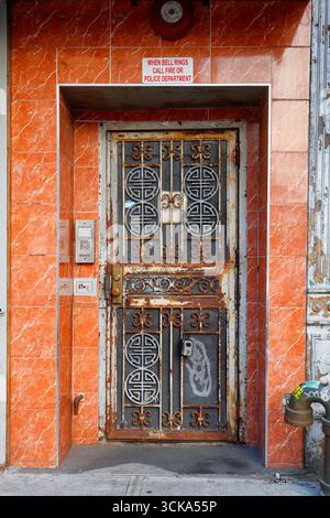A rusty metal gate with Oriental Asian design elements framed by an orange tile doorway. Stock Photo