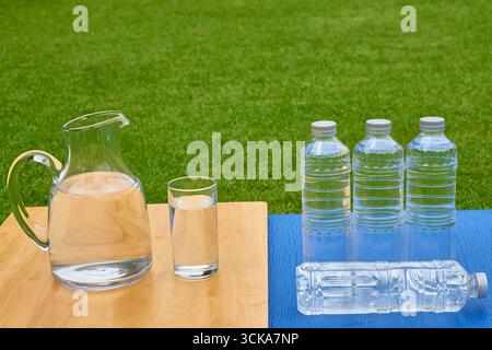 A comparison between a reusable glass jug and disposable plastic bottles. A concept for choosing sustainable alternatives, reducing plastic waste, and Stock Photo