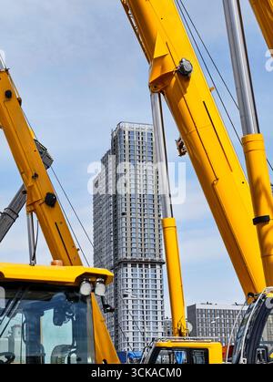 Construction activity showcases tall building under construction surrounded by machinery in urban setting on a clear day Stock Photo